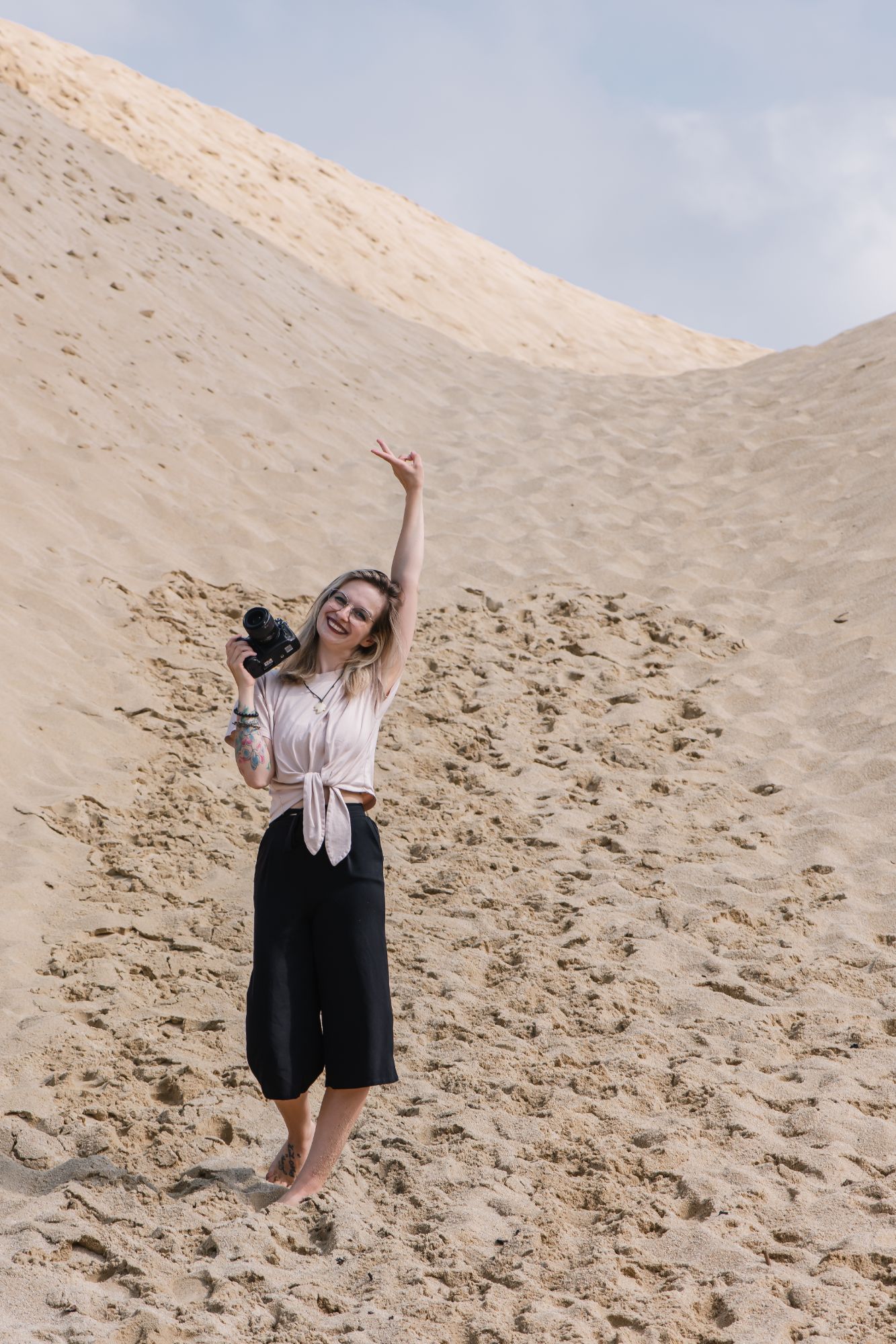 Sarah, Hochzeitsfotografin von Sarahs Fotostube, mit Kamera in den Dünen